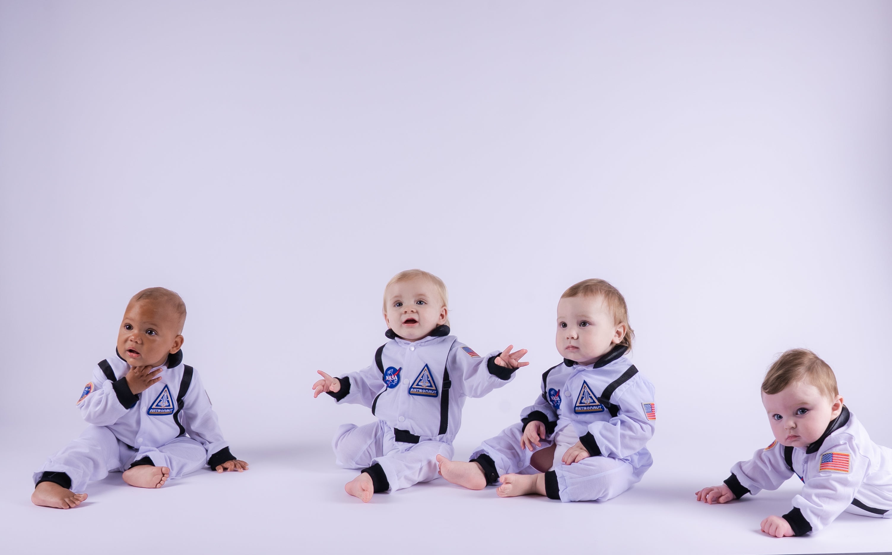 Four babies in astronaut costumes on a white background